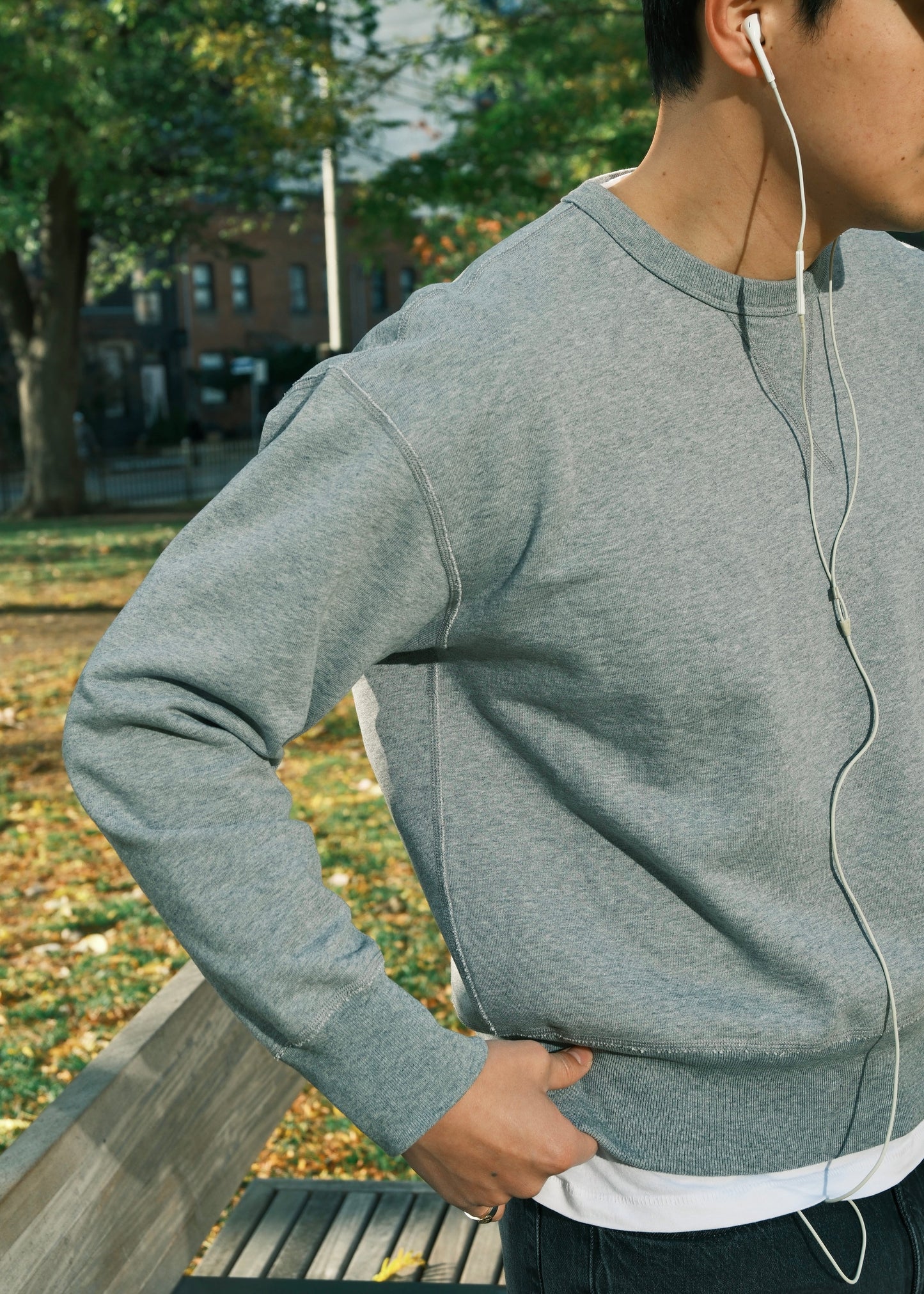 Light grey crewneck sweatshirt for men, shown layered over white tee in outdoor setting.