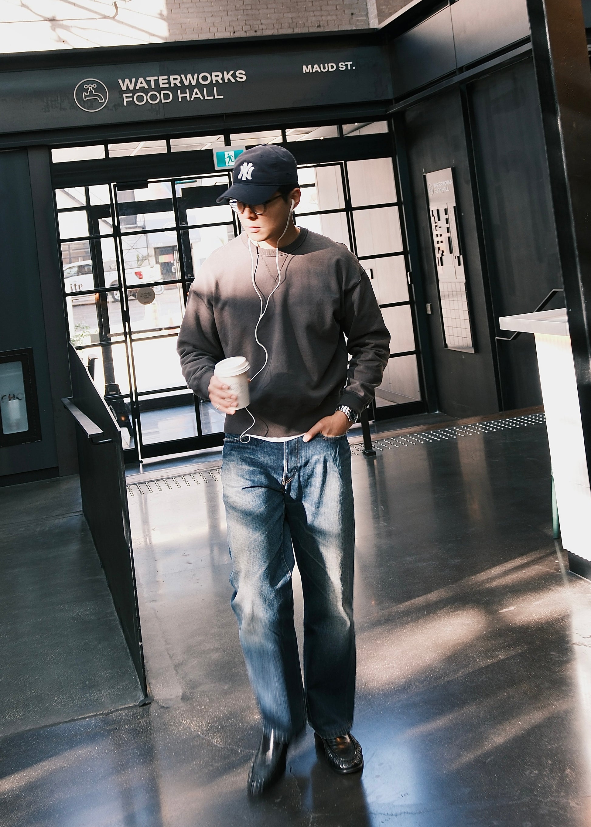Black crewneck sweatshirt styled casually with blue washed jeans, in an indoor setting. 