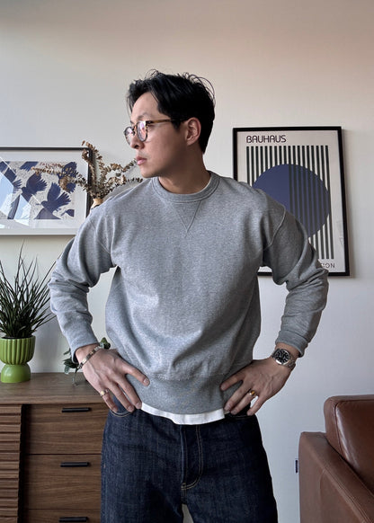 Man wearing a gray sweater and glasses in a room with decor elements.