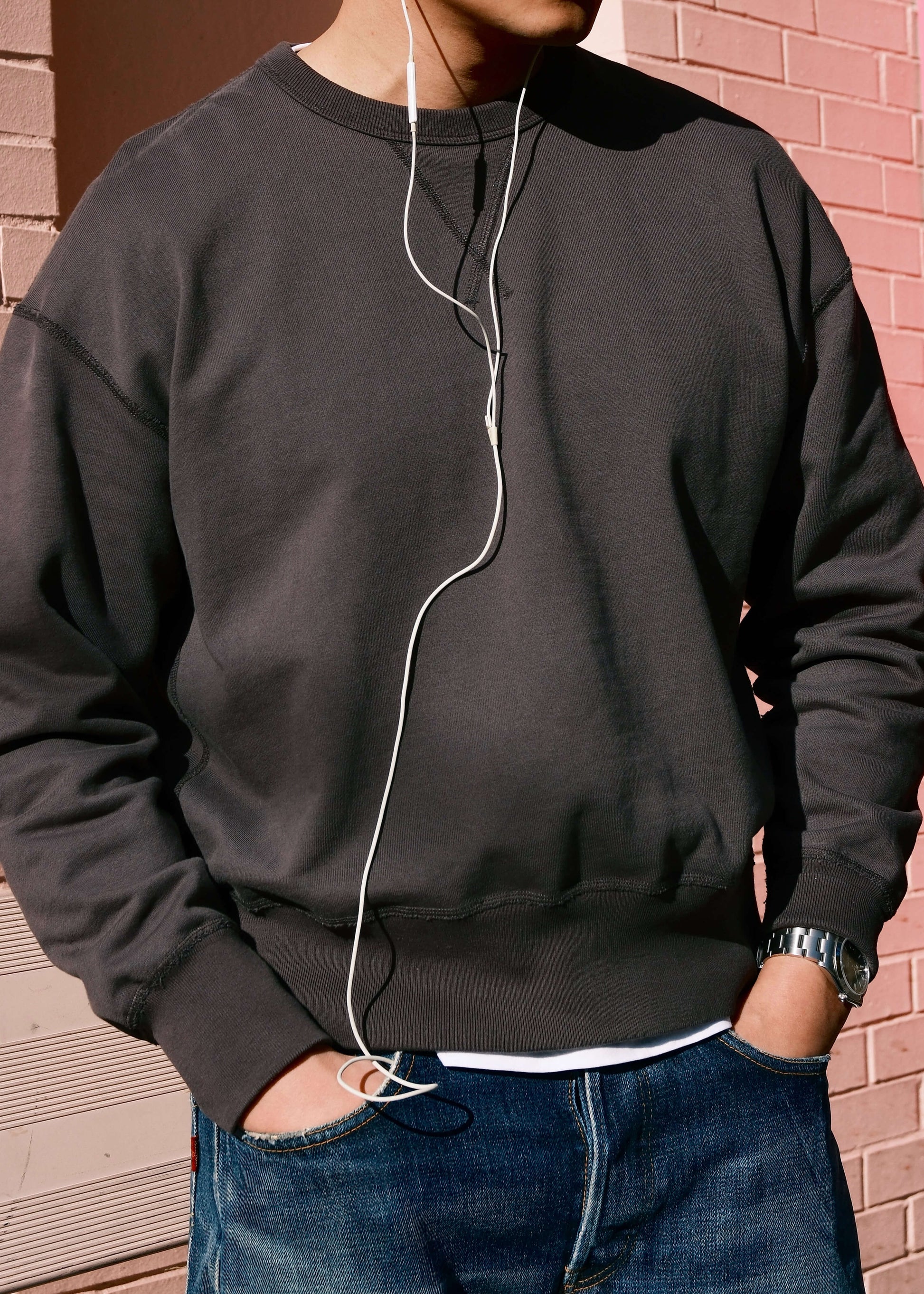 Black crewneck sweatshirt for men, shown layered over white tee in outdoor setting.